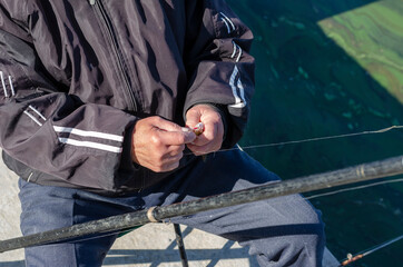 A 70-75 year old man removes a small fish from the hook.