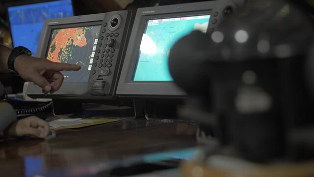 A hand is pointing at navigation and sailing monitors used by the captain of the cruise.