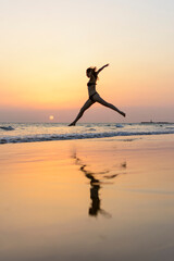 woman jumping on the seashore at sunset