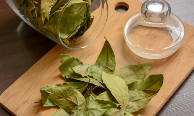 Dried bay leaf (spice) on a wooden cutting board on a dark background