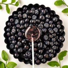 Homemade lollipops made from natural dehydrated bilberry on a white wooden background. Healthy vegan vegetarian food with no sweets.
