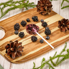 Homemade lollipops made from natural dehydrated bilberry and blackberries on a white wooden background. Healthy vegan vegetarian food with no sweets.