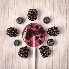 Homemade lollipops made from natural dehydrated bilberry and blackberries on a white wooden background. Healthy vegan vegetarian food with no sweets.