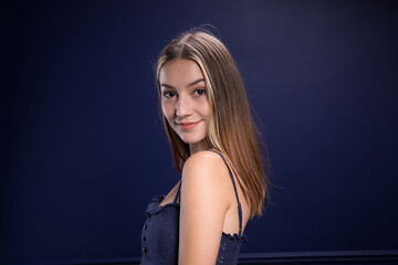 Naklejka premium A beautiful woman in a blue dress against a blue wall. 