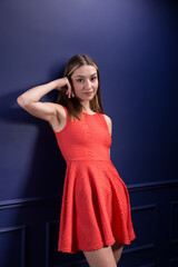 A beautiful woman in a red dress against a blue wall.