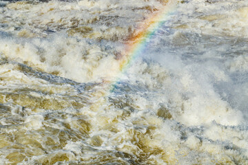 Splashing water waves with rainbow on the fast river
