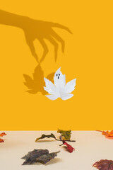 Halloween minimal concept with autumn leaves and witch or zombie hand shadow. Creative spooky ghost. Holiday fun background