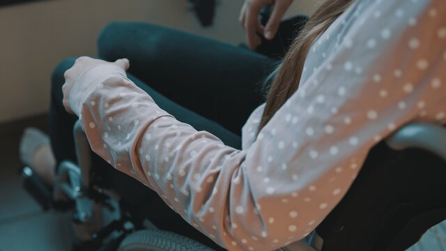 Close up, hand of the young dissabled woman recovering in the wheelchair. High quality photo