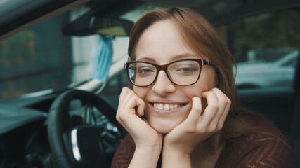 Fototapeta na wymiar Close up, Face expression of young caucasian woman sitting on the driver seat. Face mask hanging on the mirror. High quality photo