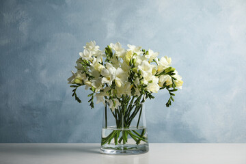 Beautiful freesia flowers in vase on white table