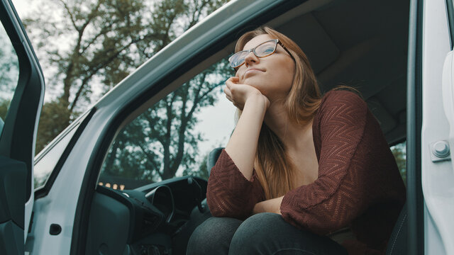 Young caucasian woman driver with open cars door looking at the distance. High quality photo