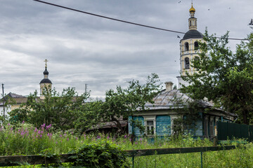 Domes and a bell tower rise above the garden and the house. View from the suburb. Panfutyevsky...