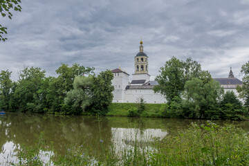 The bell tower, walls, towers with loopholes are reflected in the water. View from the pond....