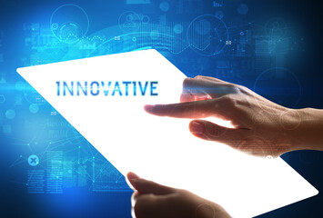 Hand holdig futuristic tablet with INNOVATIVE inscription, new technology concept