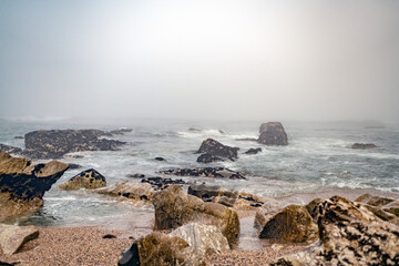 Fototapeta na wymiar Magische-Mystisches Meer. Nebel, Fog, Mist, Wolken, Wellen, Steine am Strand mit Blick auf den ewigen Ozean.