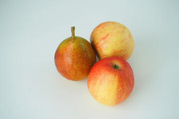 Two ripe apples and one beautiful pear on a white