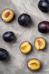 Fresh ripe plum fruits whole and sliced on stone concrete background, top view