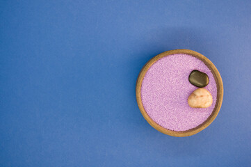 Top view shot of purple sand in a bowl isolated on blue background