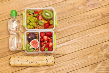 Nutritious lunch box made of fruits, berries and nuts. Bottle of water and pie