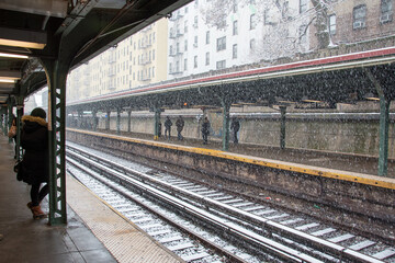 Fototapeta premium gros flocons de neige tombant sur les rails d'un gare avec des passagers attendant sur les quais 