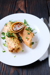 Chickpea crepes filled with feta cheese and sun-dried tomato on the white plate. Homemade traditional breakfast.