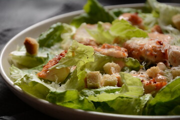 Caesar Salad with grilled chicken, Cheese and Croutons with lettuce, on plate.  Grilled chicken breasts and fresh vegetables in plate. 