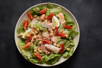 Caesar Salad with grilled chicken, Cheese and Croutons with lettuce, on plate.  Grilled chicken breasts and fresh vegetables in plate. 