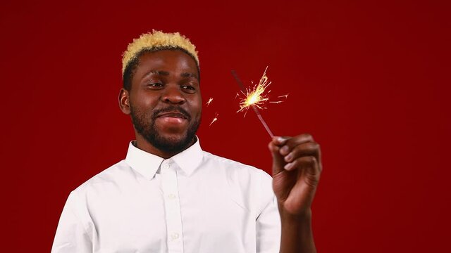 african american man holding a burning stick of dynamite in studio red background