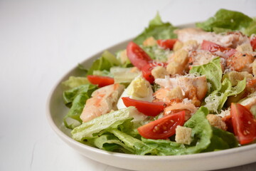 Caesar Salad with grilled chicken, Cheese and Croutons with lettuce, on plate.  Grilled chicken breasts and fresh vegetables in plate. 