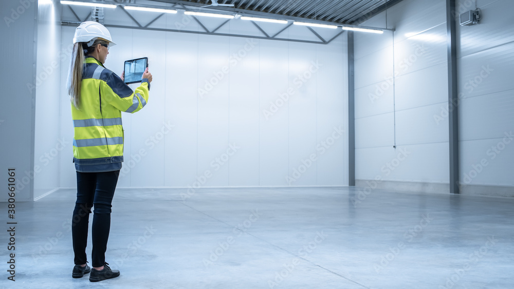 Poster Industry 4.0 Modern Factory: Female Engineer is Stanging in Empty Warehouse and Using Digital Tablet Computer with Augmented Reality Software for Mapping Manufacturing Plant Room, Factory Layout.