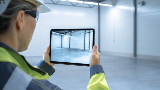 Industry 4.0 Modern Factory: Female Engineer Uses Digital Tablet Computer with Augmented Reality Software Visualizing of Manufacturing Plant Room Mapping, Factory Layout. Concept Shot Suitable for AR. - Powered by Adobe