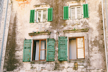 Fototapeta na wymiar An old multi-storey building with windows and wooden shutters with peeled paint.