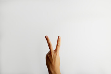 Female hand shows two fingers on white background with free space for text