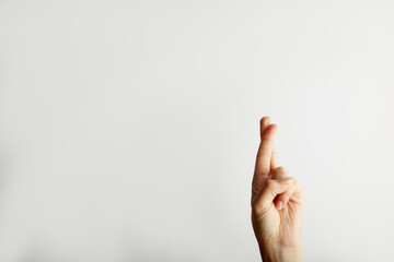 Female hand crossing fingers for hope, on white background with free space for text