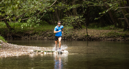 Fototapeta na wymiar Young man in sports equipment running in mountain river