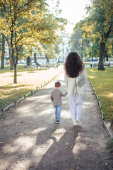 Little boy walks with his mom in autumn park