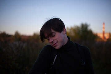 Portrait of a guy in the sunlight. Young man in nature. A student is skipping school in the woods. A guy with a regular haircut. A young man of European appearance. A man on a summer day.