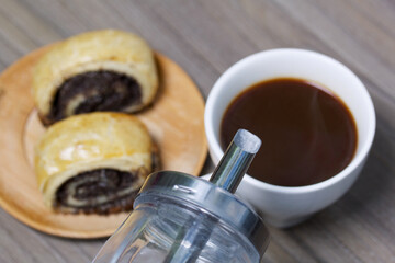 Baked buns with poppy burgers. Lie on a plate. Nearby is a cup of coffee and a sugar bowl.