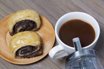 Baked buns with poppy burgers. Lie on a plate. Nearby is a cup of coffee and a sugar bowl.