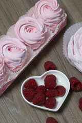 Pink marshmallow in a gift box. Nearby is a bouquet of some raspberries.