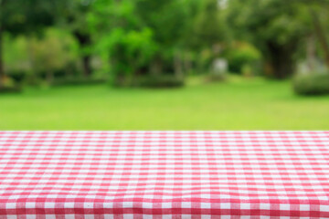 Red checkered tablecloth texture top view with abstract green bokeh from garden in morning background.For montage product display or design key visual layout and summer season.