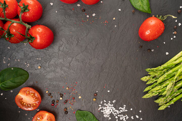 omatoes on a black board with spices and asparagus with copy space