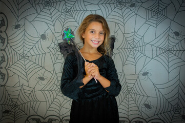 funny child girl in witch costume for Halloween over cobweb background