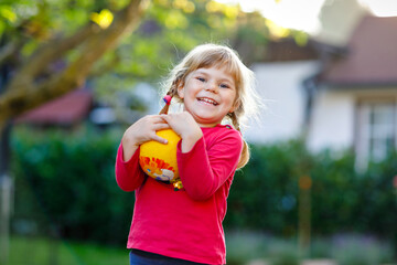 Little adorable toddler girl playing with ball outdoors. Happy smiling child catching and throwing, laughing and making sports. Active leisure with children and kids.