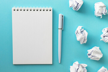 Blank notepad, pen and crumpled paper balls on bright blue background. Writing message. Вrawing up a plan. New or bad idea concept. Draw up plan. Flat lay, top view, copy space.
