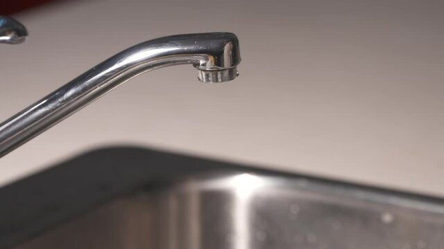 A water tap is turned on and a glass of water is filled.  The tap is then turned off again. Shot in high speed photography.