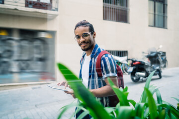 Positive strolling on street with tablet in hands