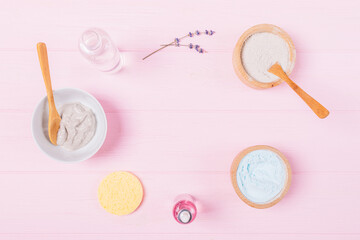 Flat lay cosmetic clay face mask with lavender aroma oil and water on pink background