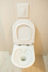 Toilet, white wall-hung toilet, rimless toilet on the walls, beige tiles. renovation in the...