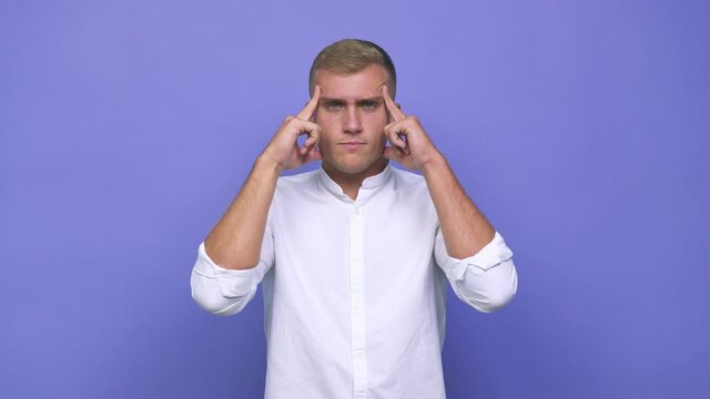 Young caucasian man focused on a task, keeping forefingers pointing head